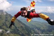 Skysurfer is flying his board in the blue sky